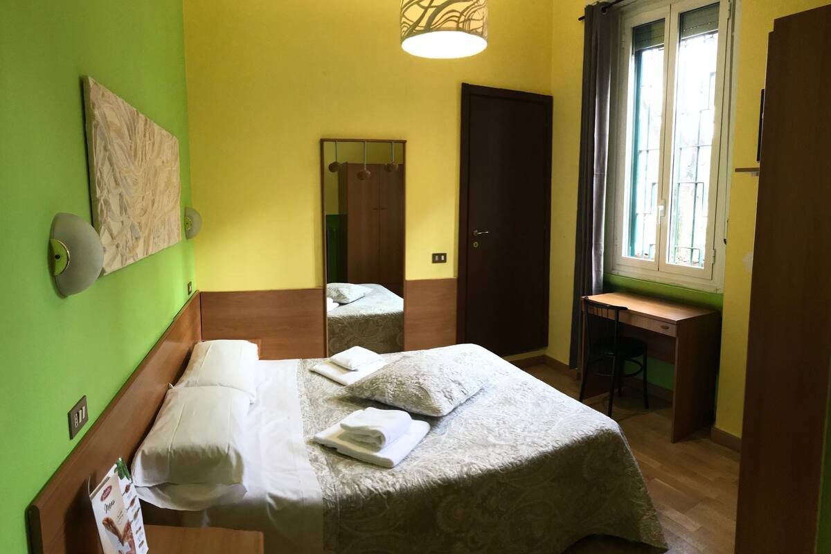 A room with two beds, a desk, and a window.