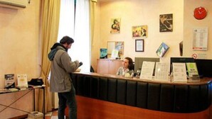 A reception desk with a counter, a clock, and a few framed pictures on the wall. - Hotel Bogart (Milan)