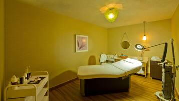 Ein Zimmer mit einem Bett, einem kleinen Schreibtisch mit Stuhl, einem Spiegel, einer Lampe und einem Regal mit Toilettenartikeln.
