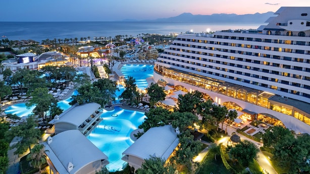 A resort with multiple swimming pools, a large hotel building, and a view of the sea. - Titanic Deluxe Lara - All inclusive (Antalya)