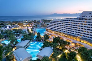 A resort with multiple swimming pools, a large hotel building, and a view of the sea. - Titanic Deluxe Lara - All inclusive (Antalya)