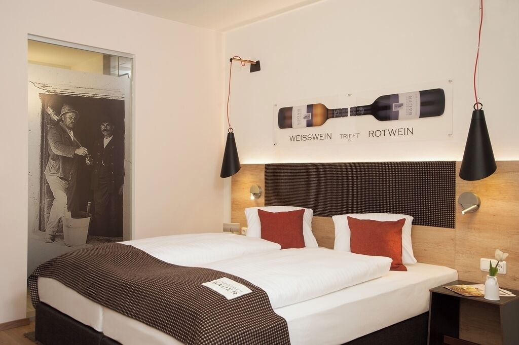 A hotel room with a large bed, a headboard with a wine bottle display, and a wall-mounted picture.