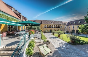 Un patio con mobiliario exterior, una escalera y un edificio con arcos.