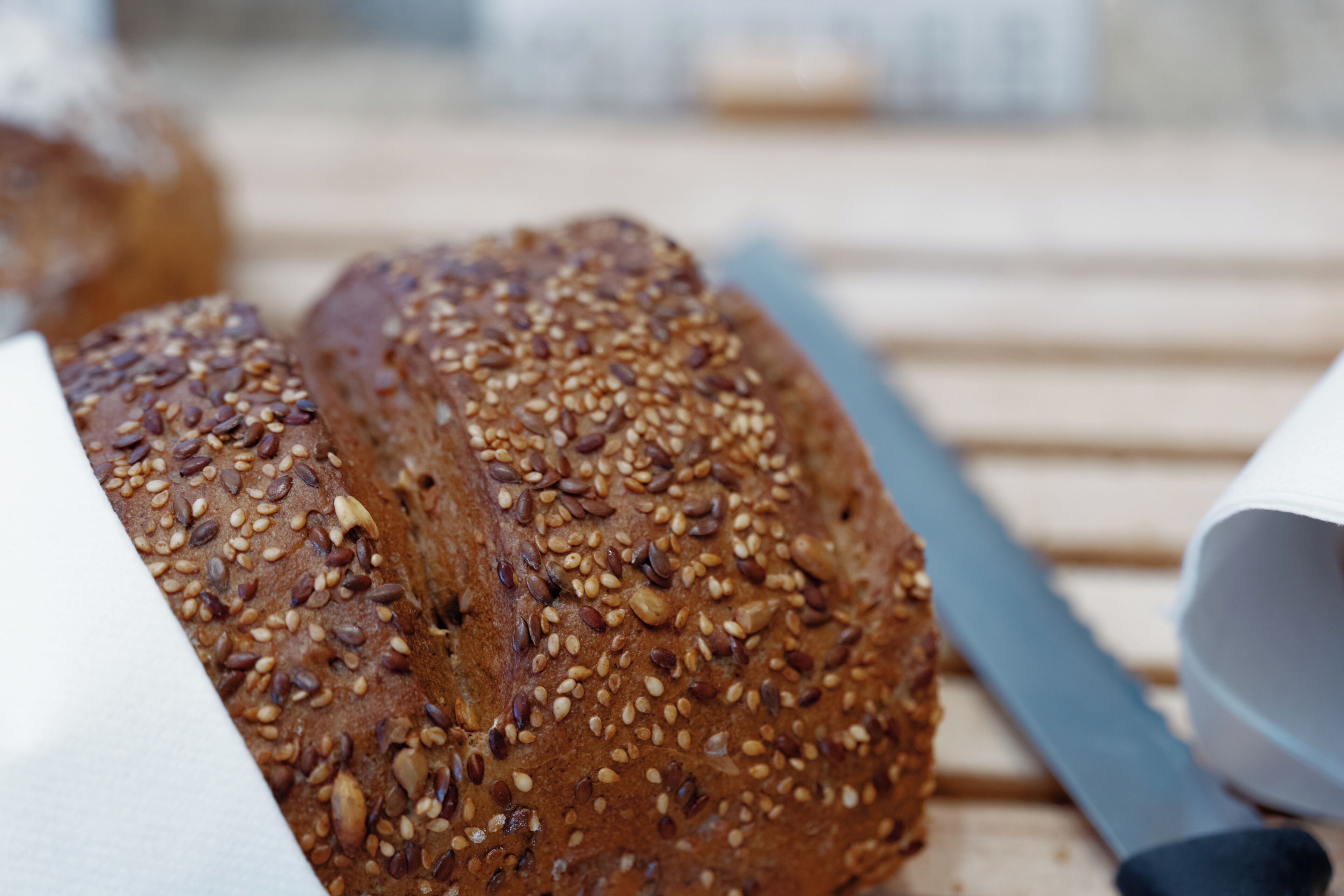 A loaf of seeded bread on a wooden surface.
