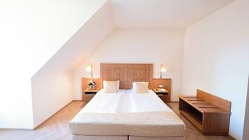 Un dormitorio con una cama grande, cabecera de madera, mesitas de noche con lámparas y un banco.