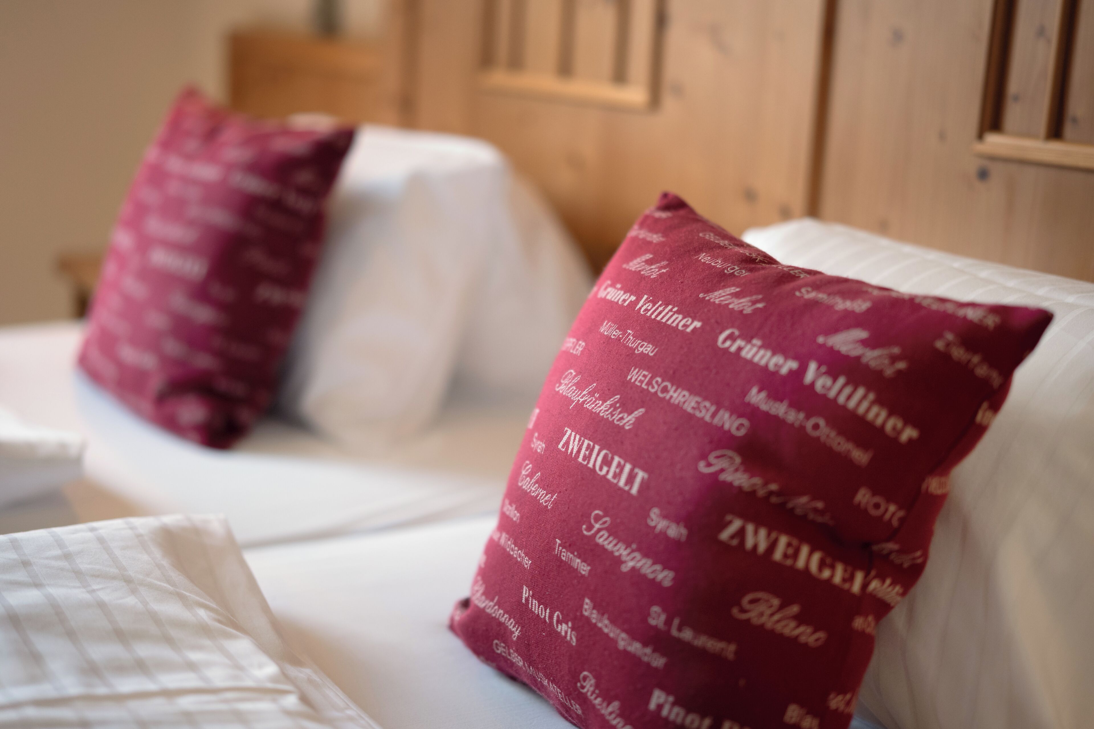 A bed with white bedding and two pillows with text patterns.