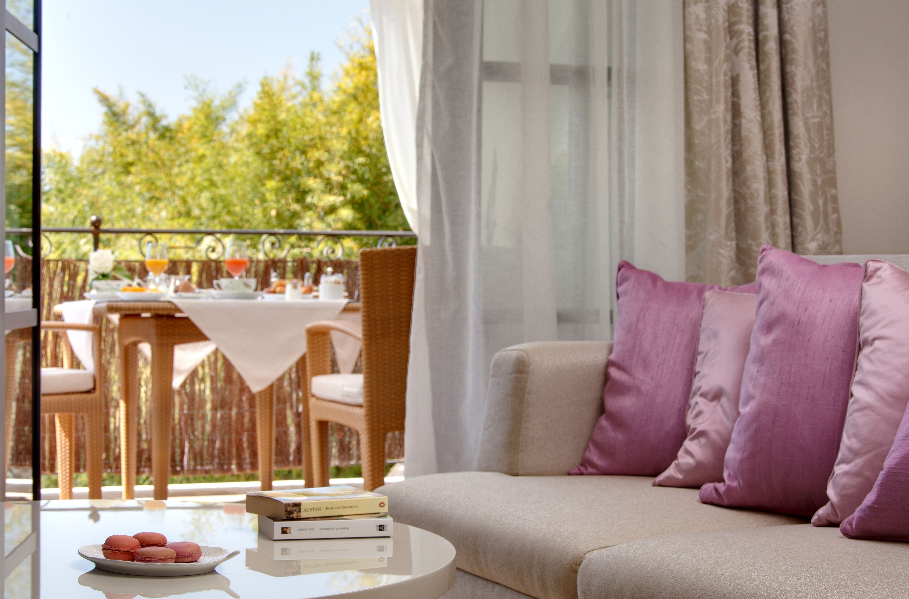 Un balcón con mobiliario de mimbre y una mesa para dos, con vistas a un jardín.