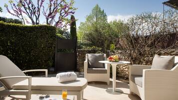 Un patio con mobiliario de mimbre, una mesa con un frutero y un libro.