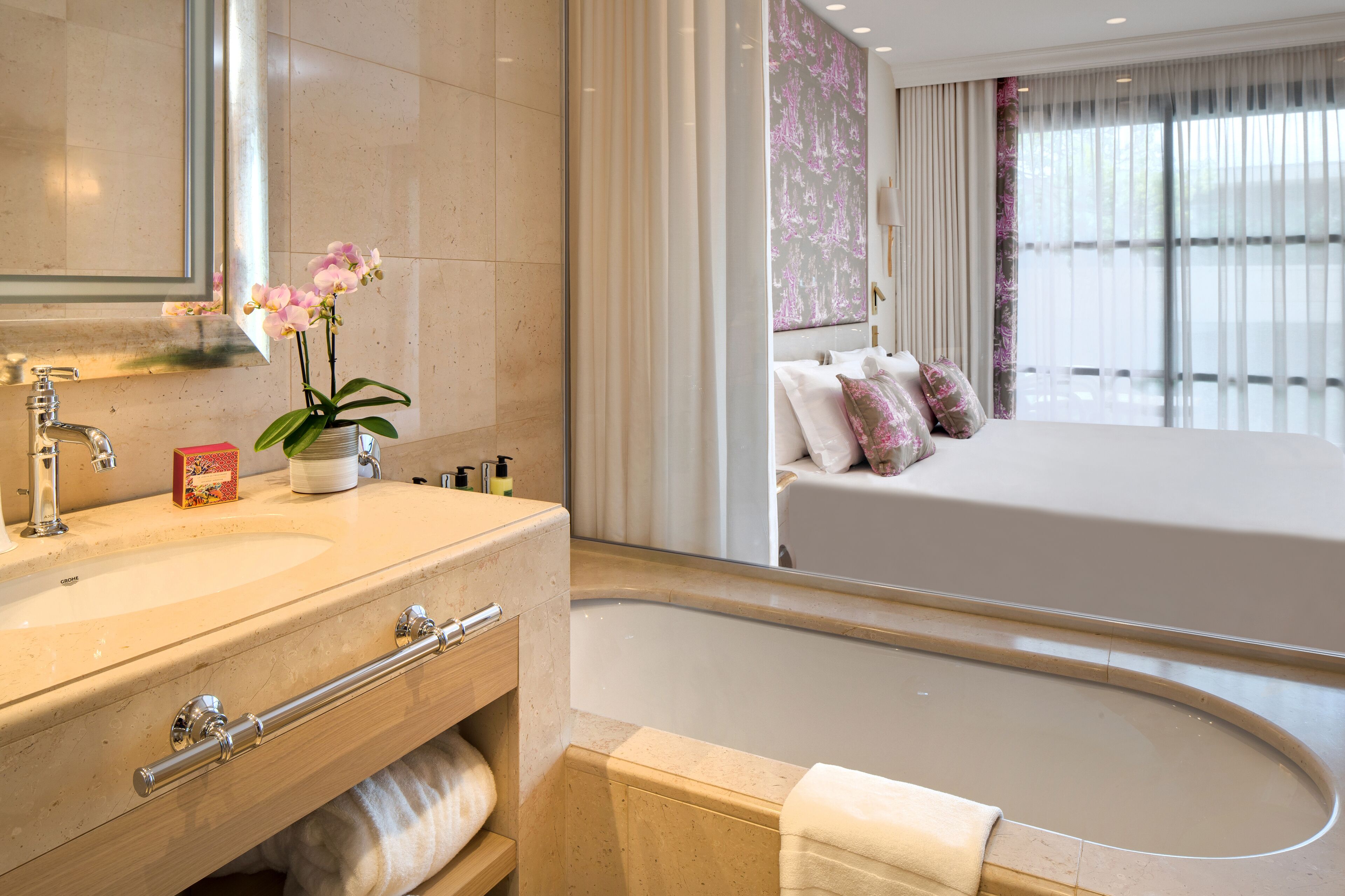 A modern bathroom with a large bathtub, a vanity with a mirror, and a potted orchid.