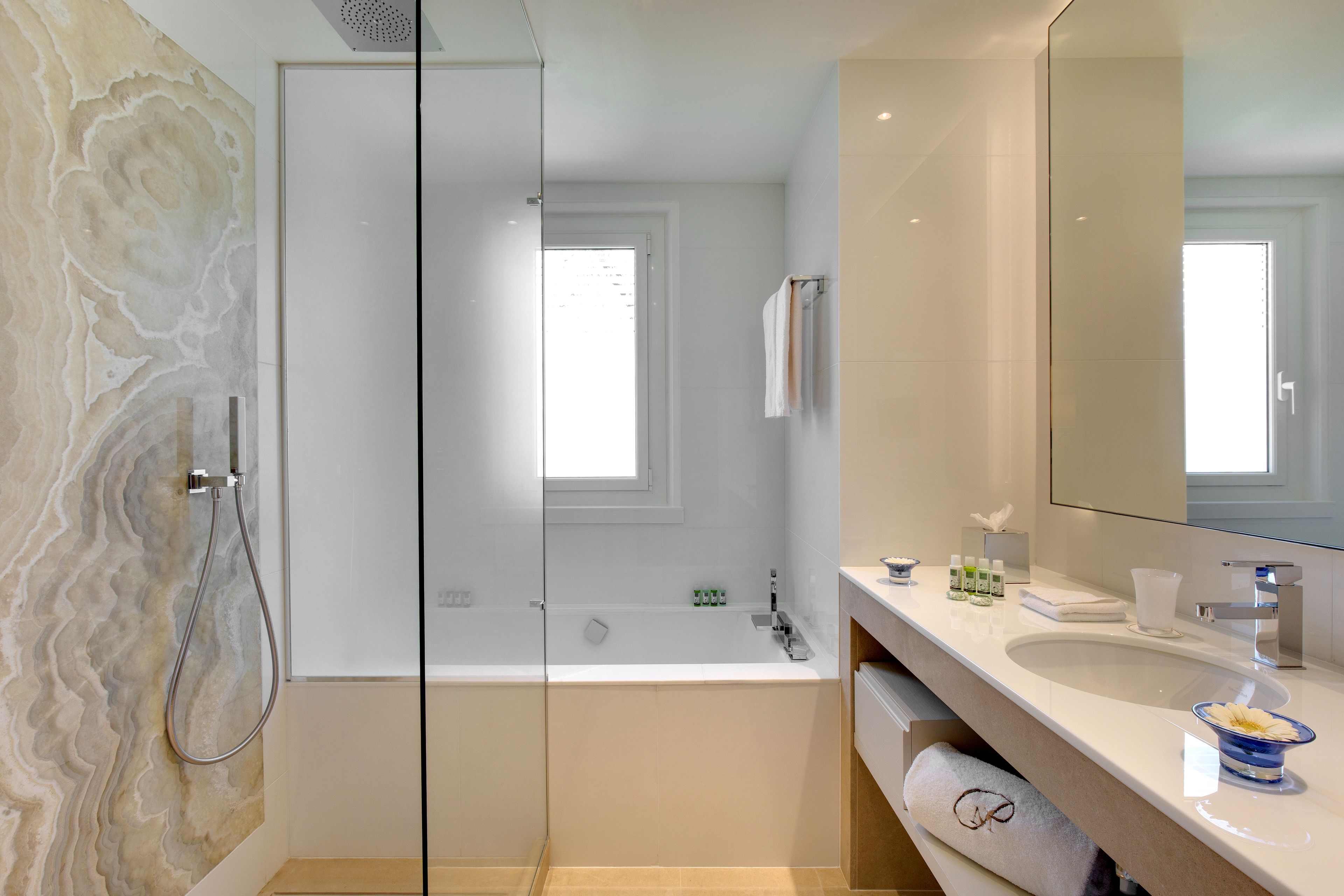 A modern bathroom with a glass shower enclosure, a bathtub, and a vanity with a large mirror.