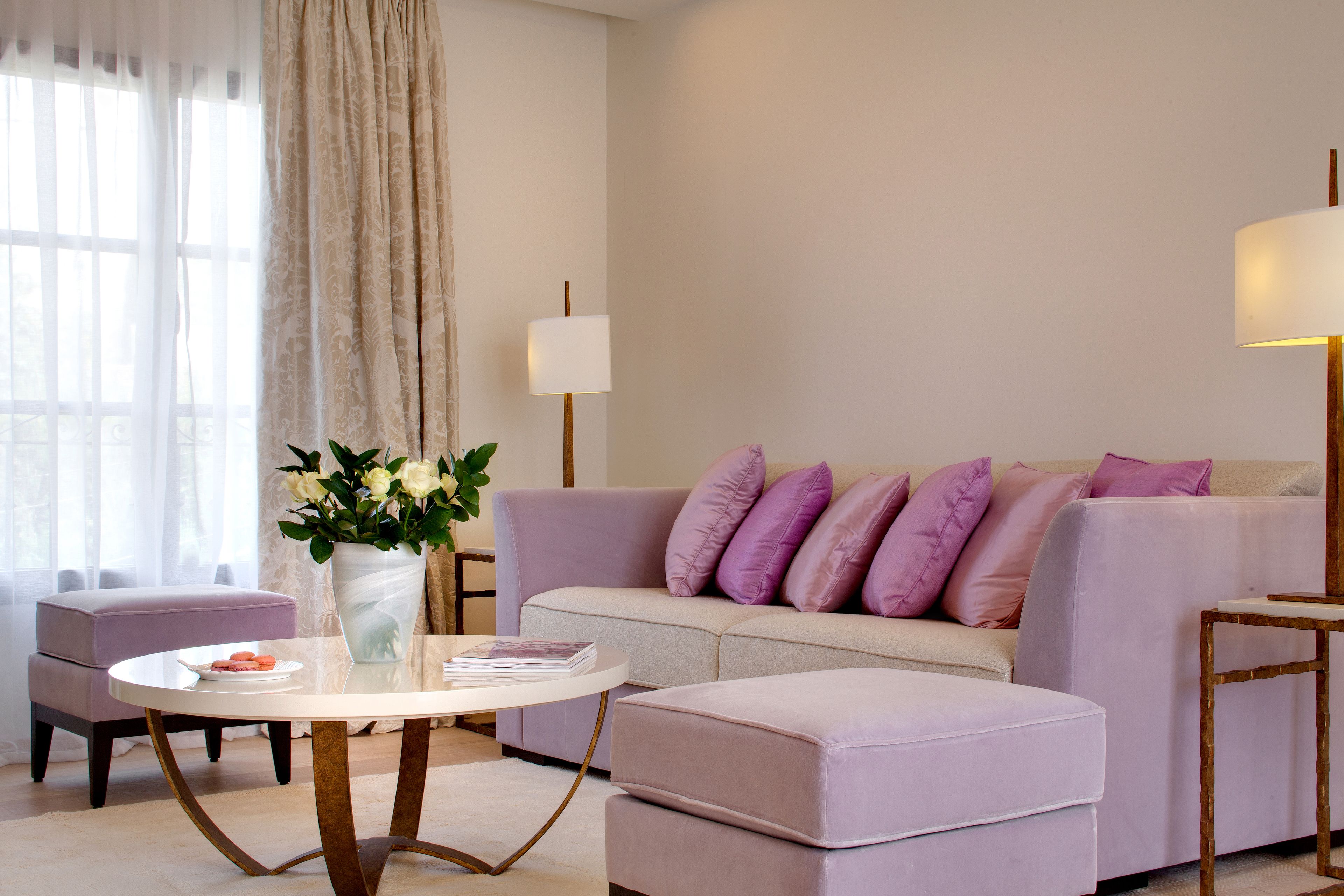 Ein modernes Wohnzimmer mit einer Couch, einem Hocker und einem runden Tisch mit Blumen.