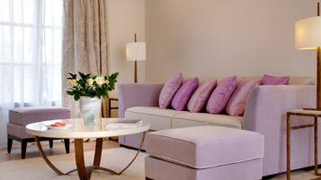 Ein modernes Wohnzimmer mit einer Couch, einem Hocker und einem runden Tisch mit Blumen.