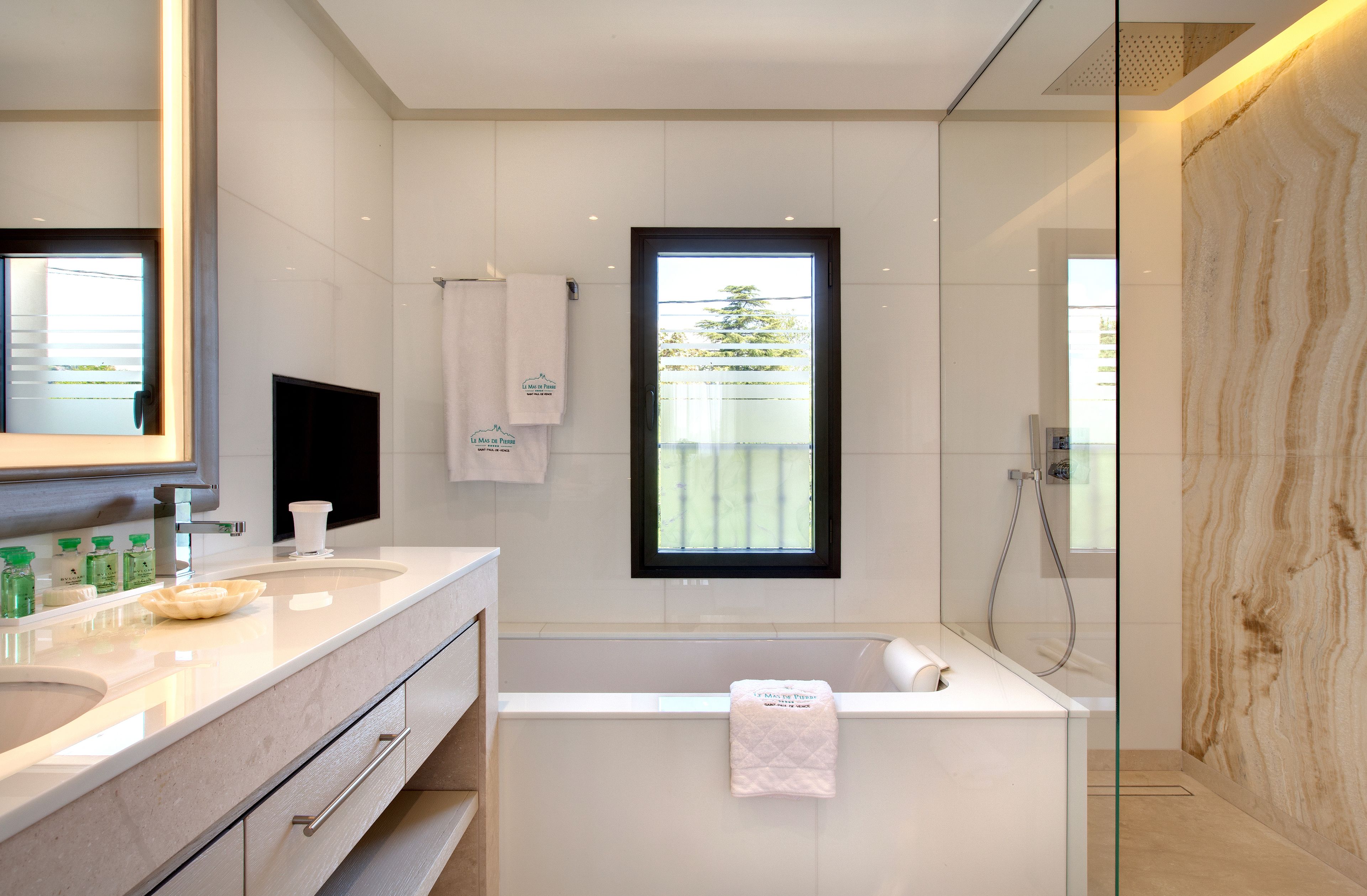 A modern bathroom with a large mirror, a bathtub, and a shower.