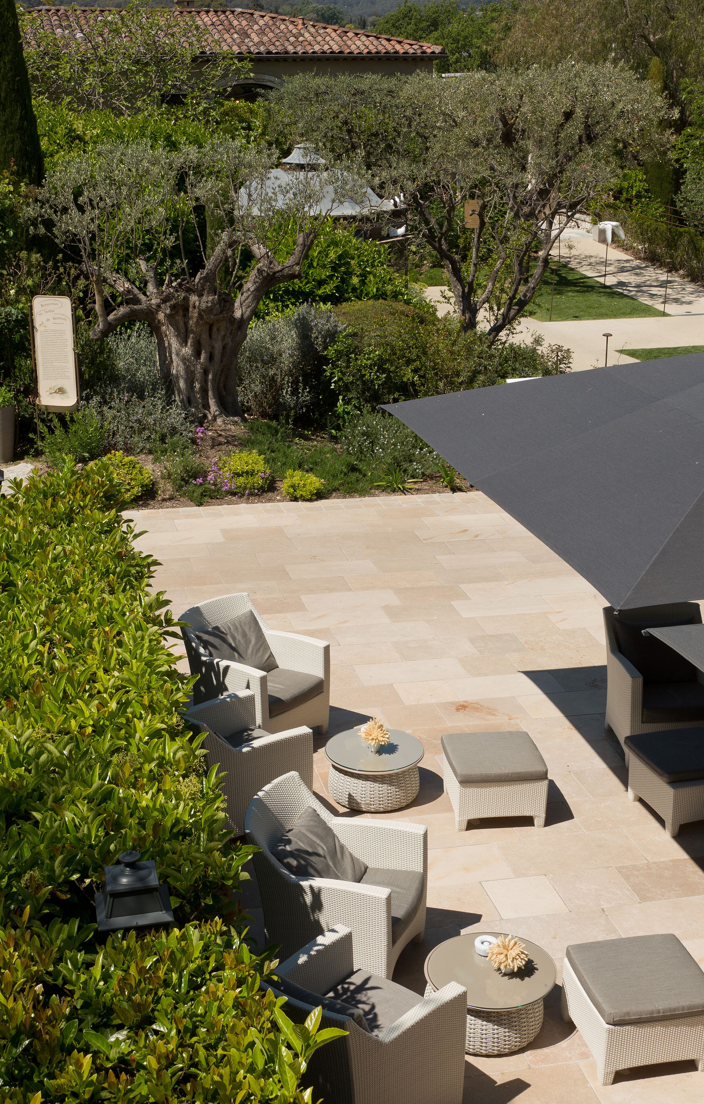 An outdoor patio with wicker furniture, a pergola, and a view of a house with a tiled roof.