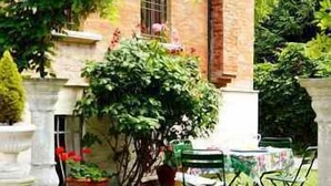 A courtyard with a brick building, a table with chairs, and potted plants.