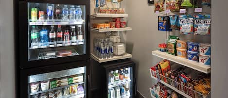 A vending machine with various drinks and snacks, a refrigerated display case with dairy products, and shelves stocked with packaged goods.