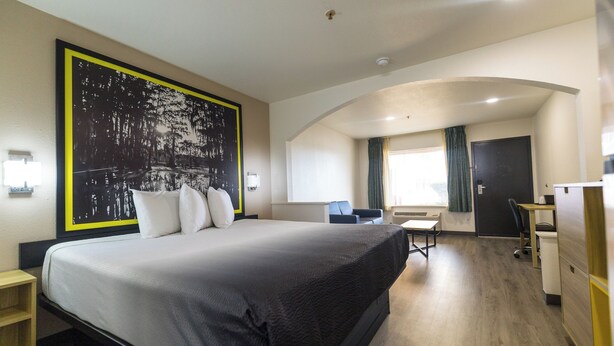 Ein Hotelzimmer mit einem großen Bett, einem Schreibtisch, einem Stuhl und einem Kleiderschrank.