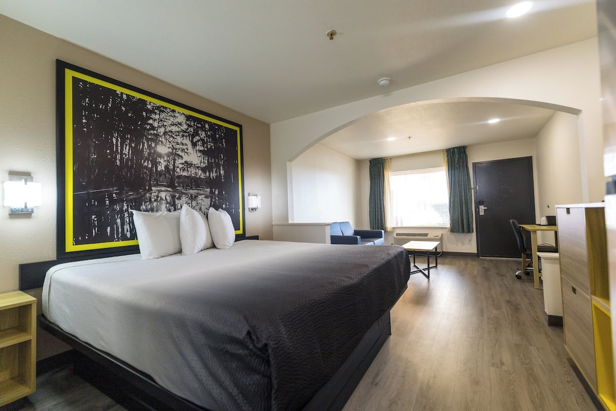 Une chambre d’hôtel avec un grand lit, un bureau, une chaise et une armoire.