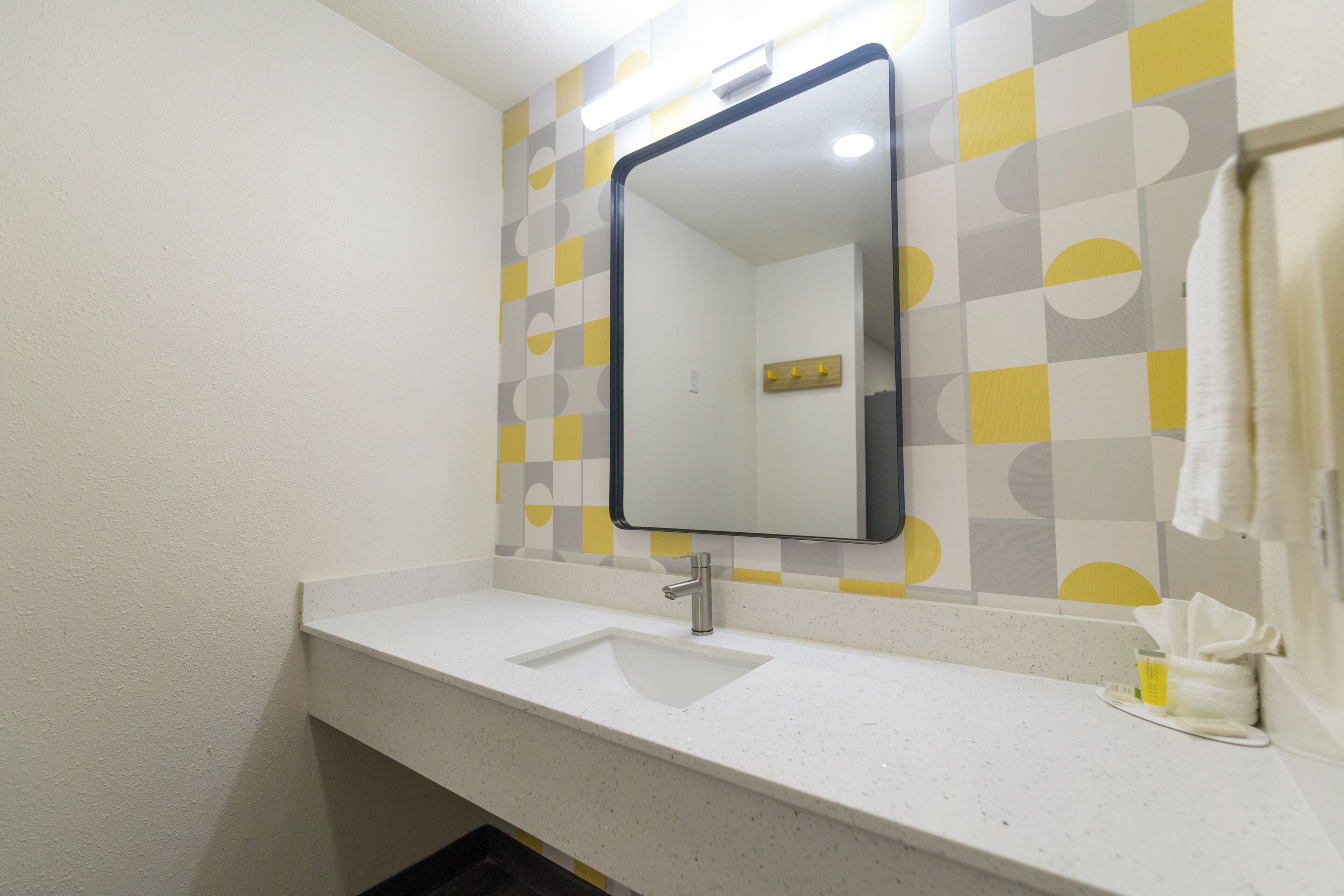 Un baño con un lavabo blanco, un espejo y una toalla colgada en la pared.