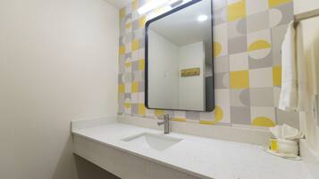 Un baño con un lavabo blanco, un espejo y una toalla colgada en la pared.