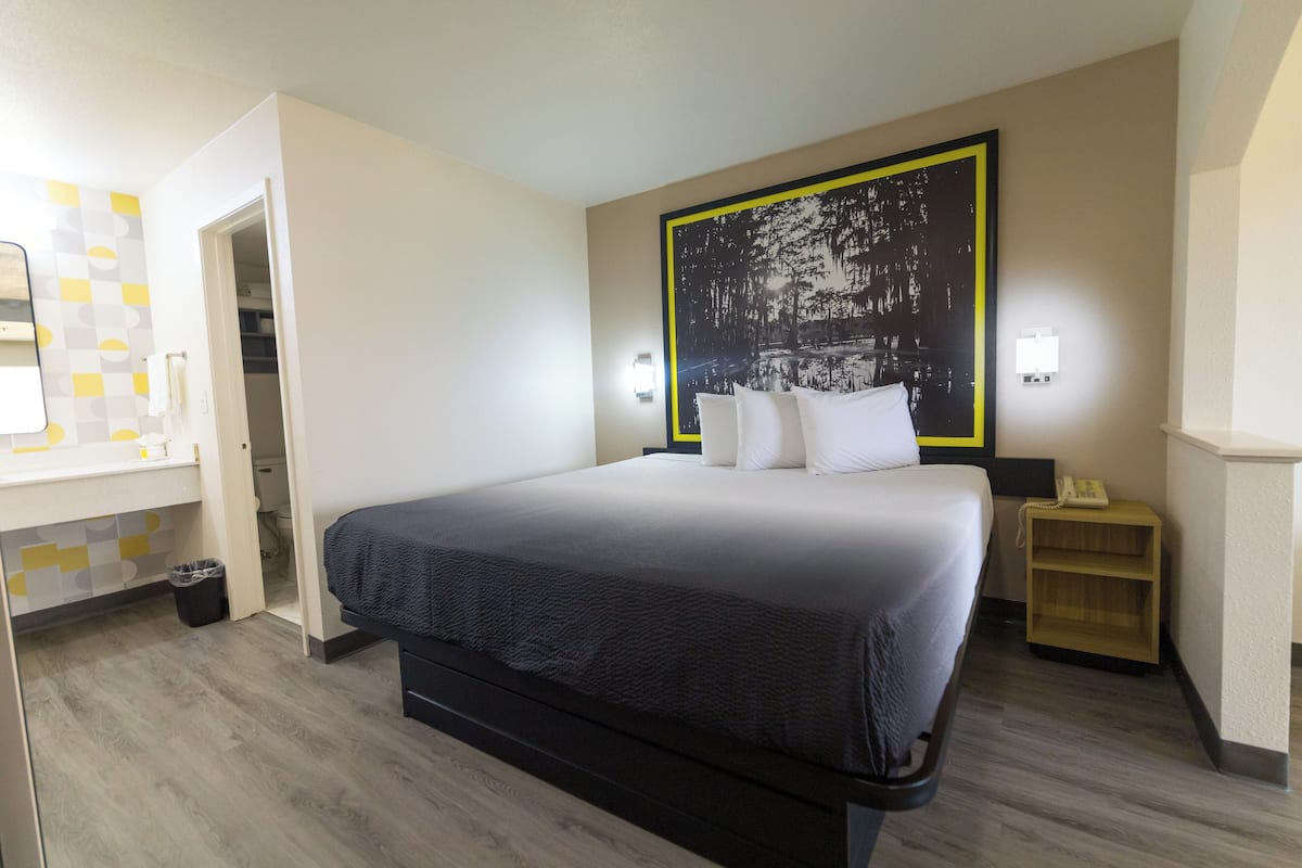 Une chambre d’hôtel moderne dotée d’un grand lit, d’une table de chevet, d’une petite table et d’une œuvre d’art accrochée au mur.