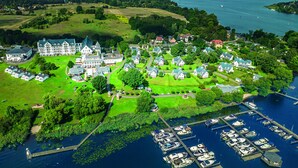 Vista aérea de una propiedad junto al lago con una mansión grande, casas más pequeñas y un puerto deportivo con barcos.