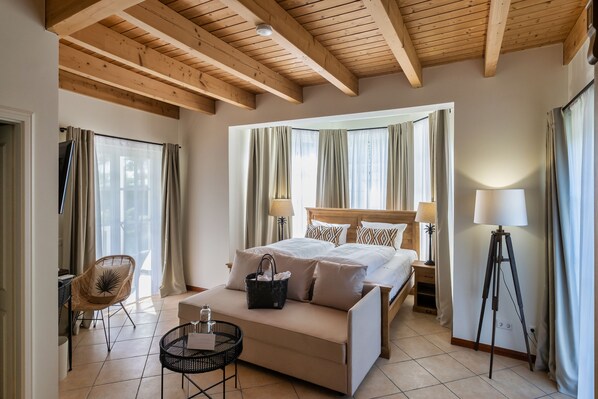 A hotel room with a wooden ceiling, a bed with white bedding, a sofa, a small table, a chair, and a floor lamp. - Sunday Resort Schwielowsee (Werder (Havel))