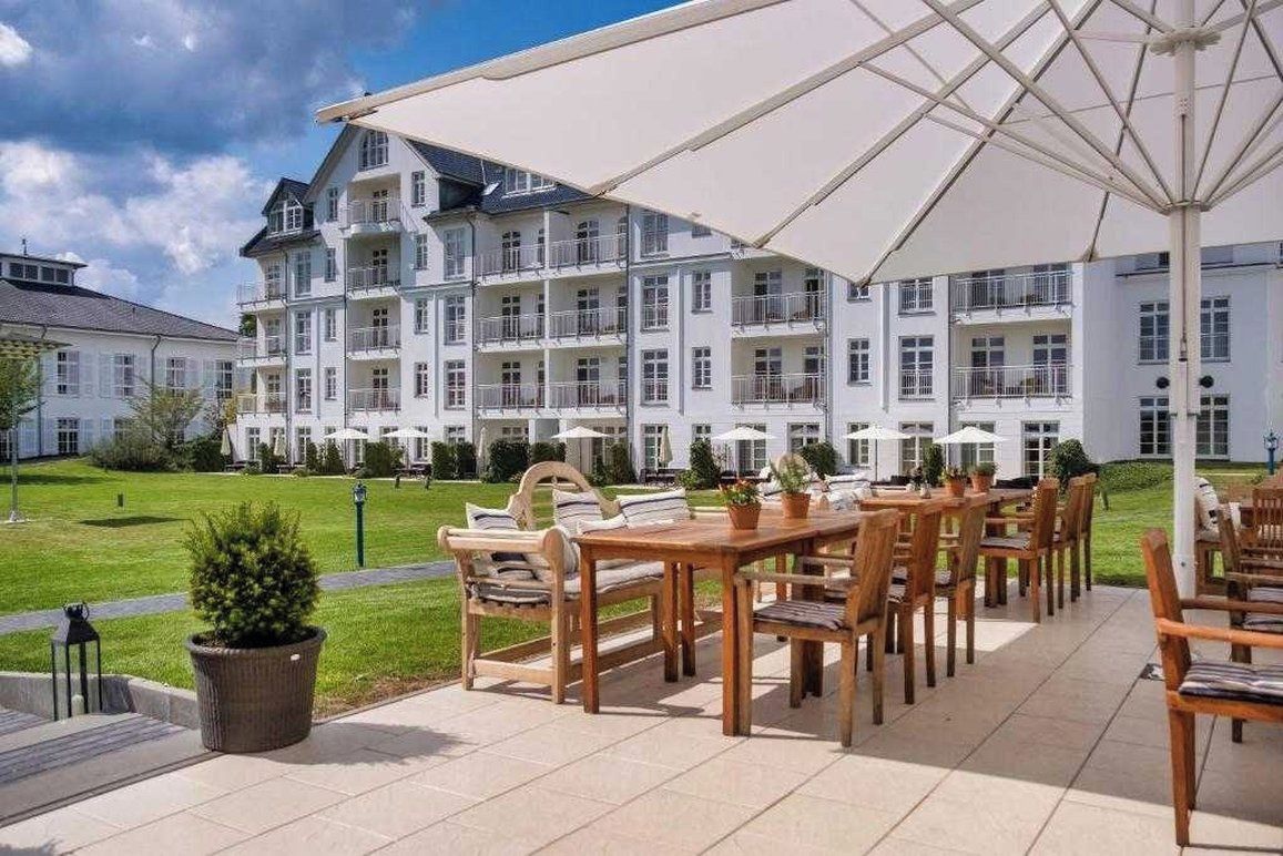 Ein Hotel mit Außenbereich, einer großen Sonnenschirm und einem gepflegten Rasen.