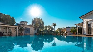 Piscina azul y transparente rodeada de casas, con un cielo soleado.