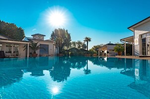 Una piscina techada, una piscina al aire libre, sombrillas