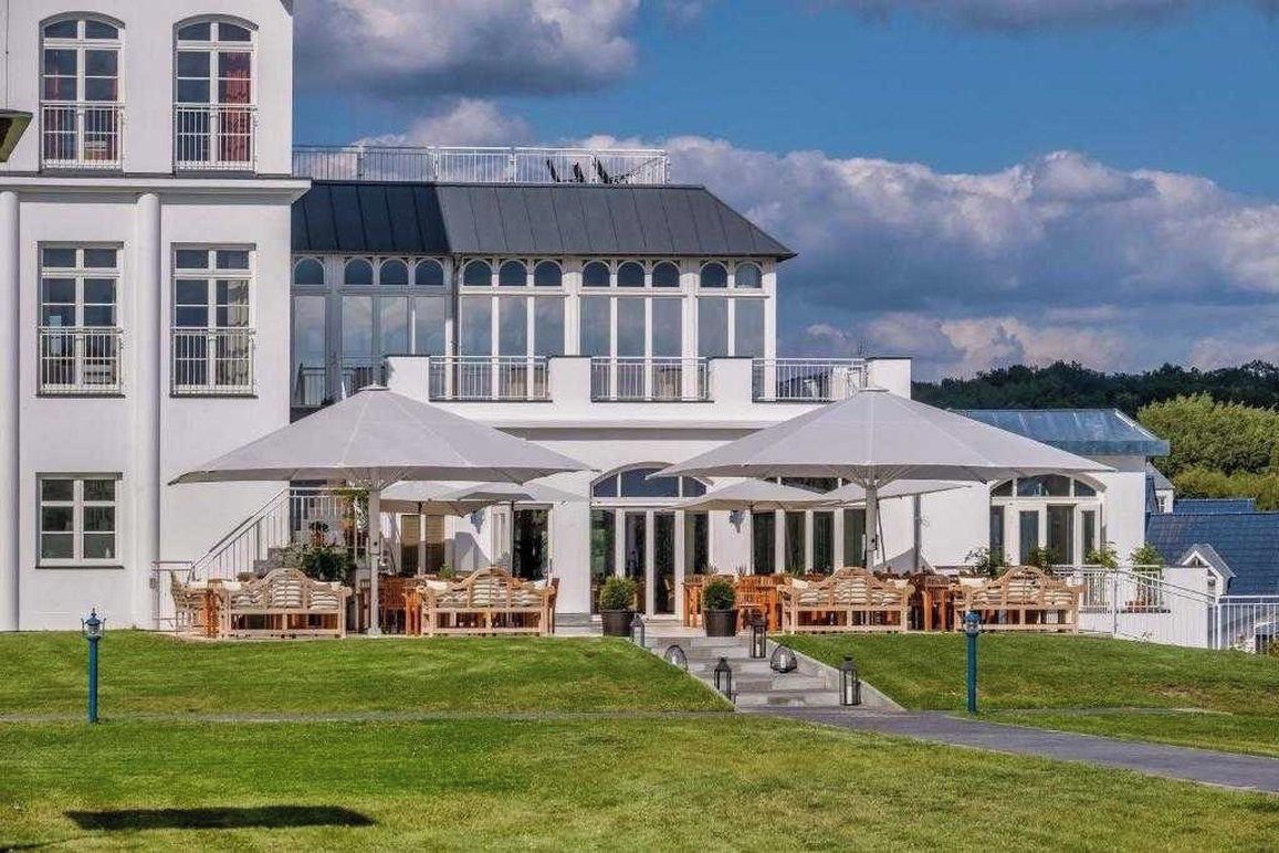 Un edificio blanco con un área de estar al aire libre techada y una escalera que lleva a un nivel superior.