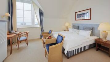 A hotel room with a bed, two bedside tables, a desk, a chair, and a window with curtains.