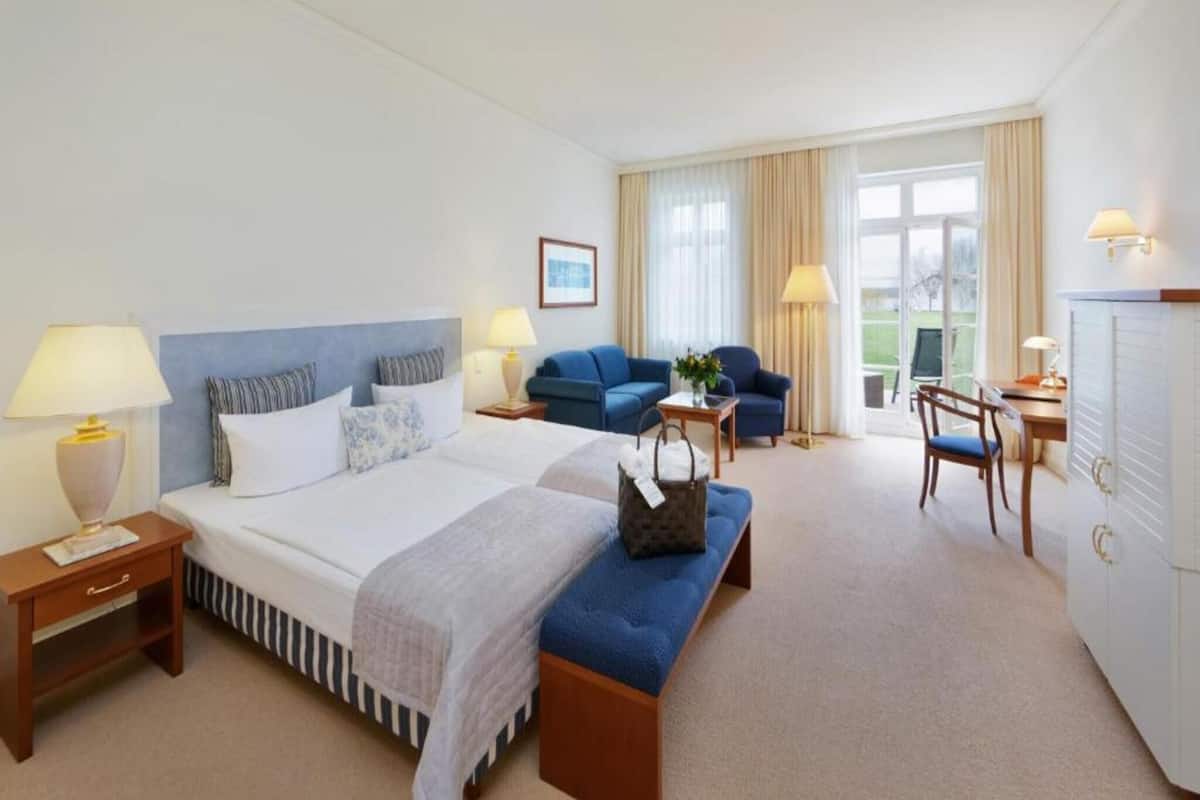 A hotel room with a large bed, a sofa, a desk, and a chair.
