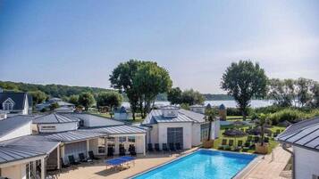 A pool area with lounge chairs and a view of the lake.