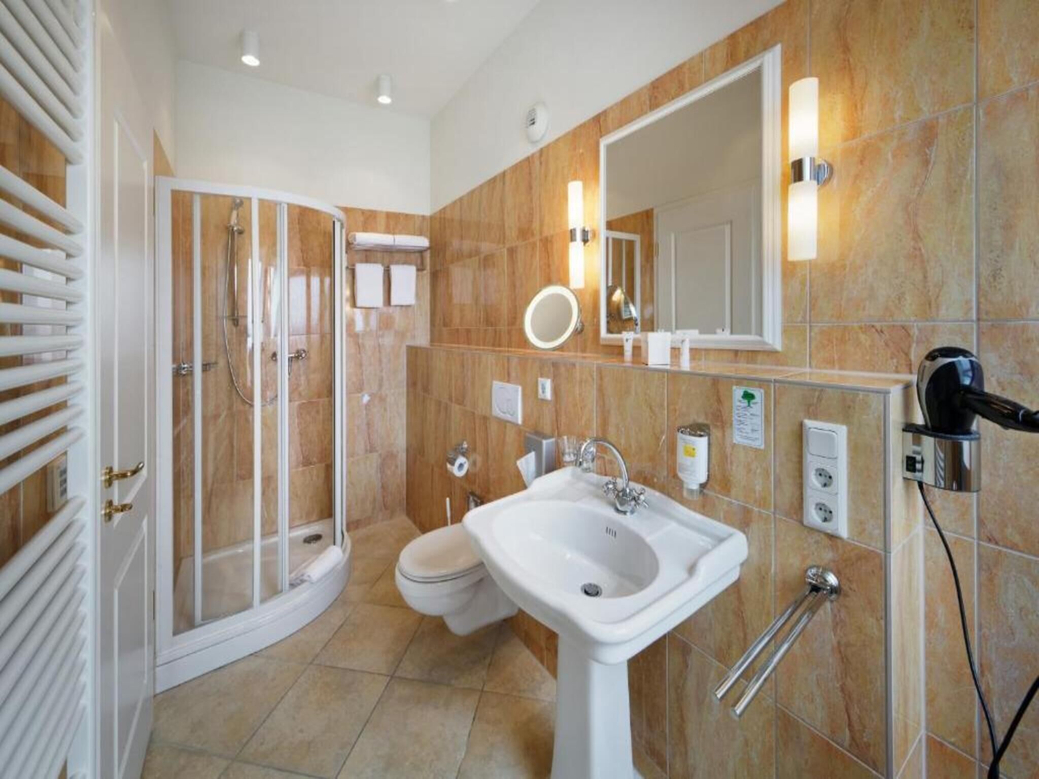 Ein Badezimmer mit Dusche, Toilette, Waschbecken und einem großen Spiegel.