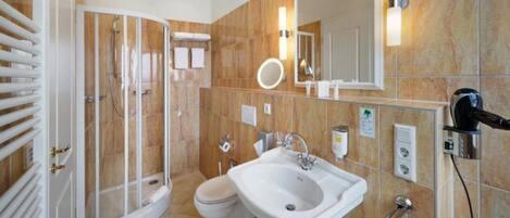 Un baño con ducha, inodoro, lavamanos y un espejo grande.