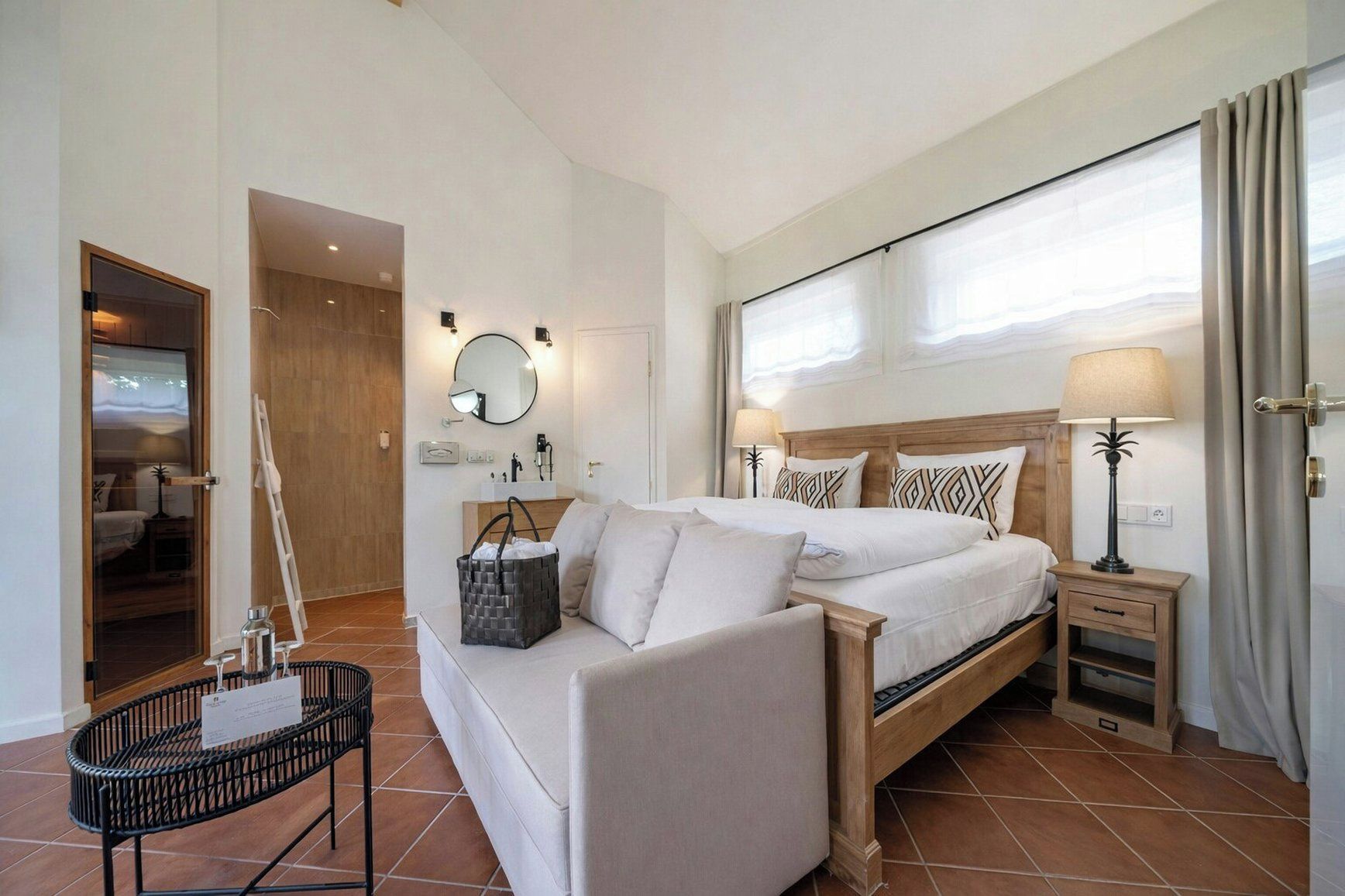 Une chambre d’hôtel moderne équipée d’un lit, de tables de chevet, d’un miroir et offrant une vue sur l’extérieur.