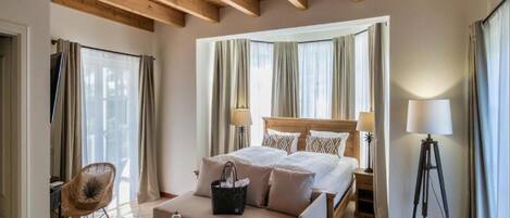 A bedroom with a bed, a sofa, a chair, a lamp, and a tripod.