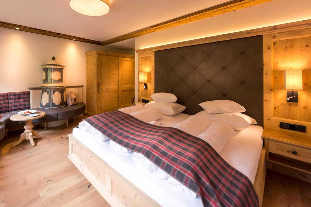 A bedroom with a bed, a small table, a sofa, and a wall-mounted heater.
