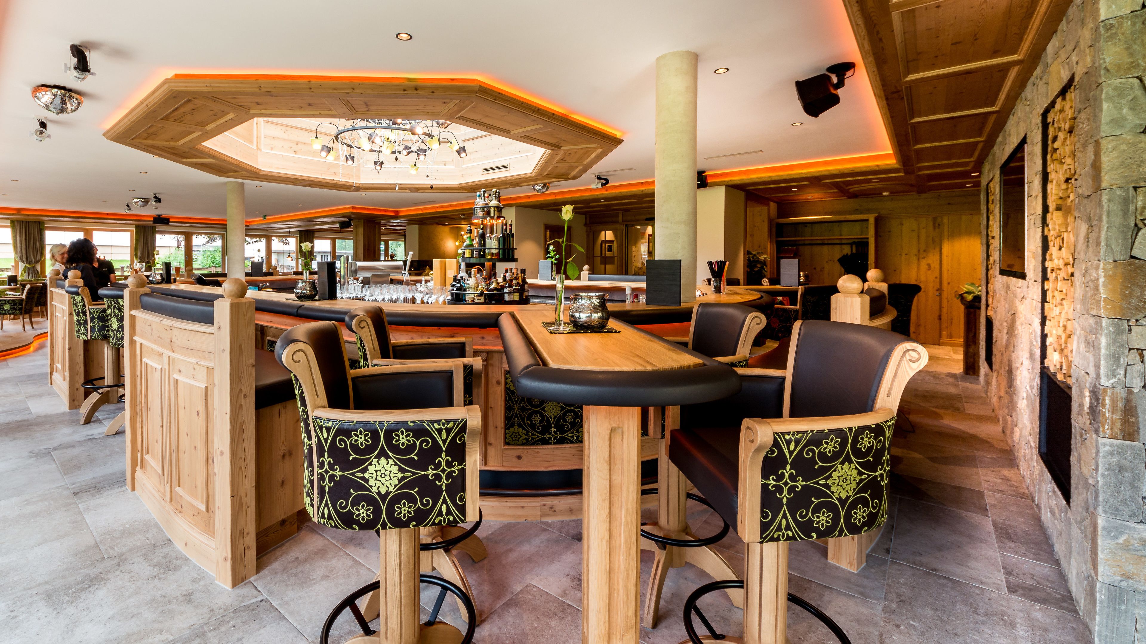 Ein Restaurant mit Holzkabinen und Tischen, einer Bar und einer Steinwand.
