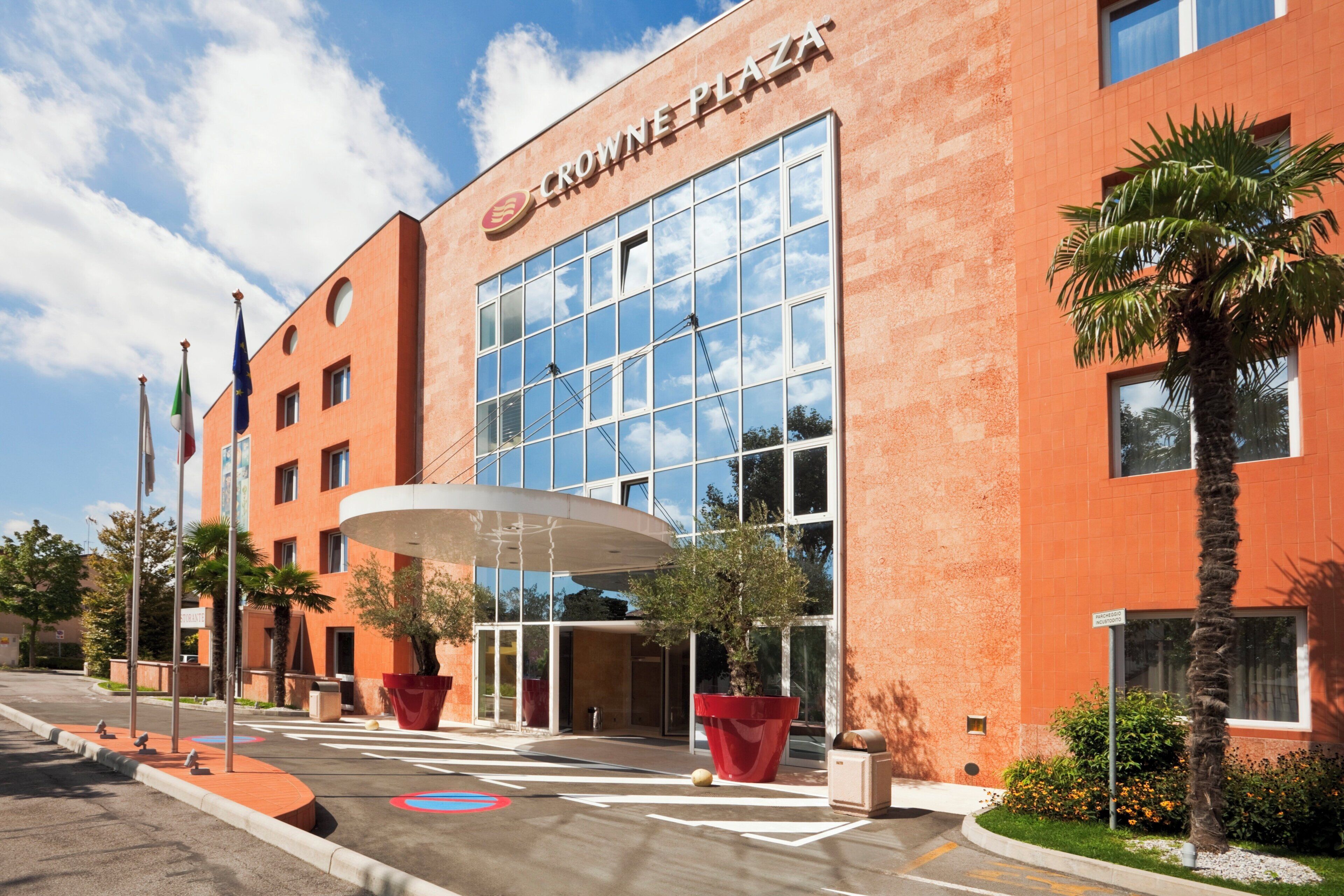 A modern building with a glass facade, a covered entrance, and a sign reading 'Crown Plaza'.