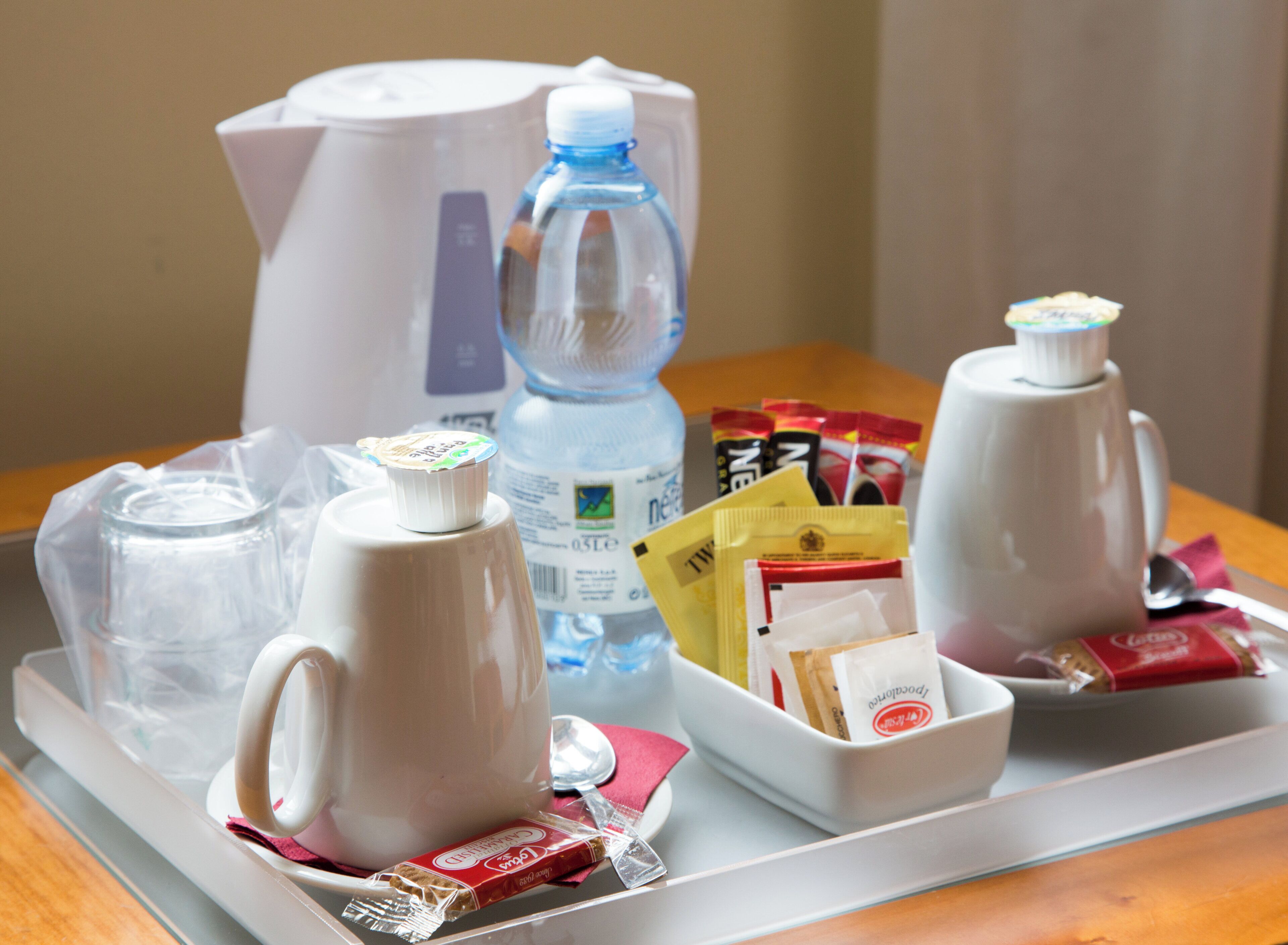 A tray with a coffee maker, a water bottle, and various food packets.