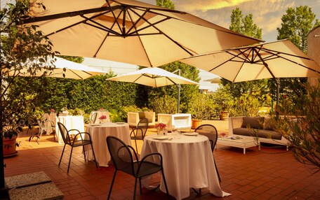 An outdoor patio with round tables, chairs, and large umbrellas.