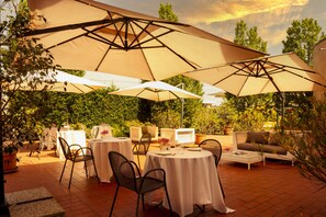 An outdoor patio with round tables, chairs, and large umbrellas.