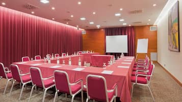 A conference room with multiple tables and chairs, a whiteboard, and a projector screen.