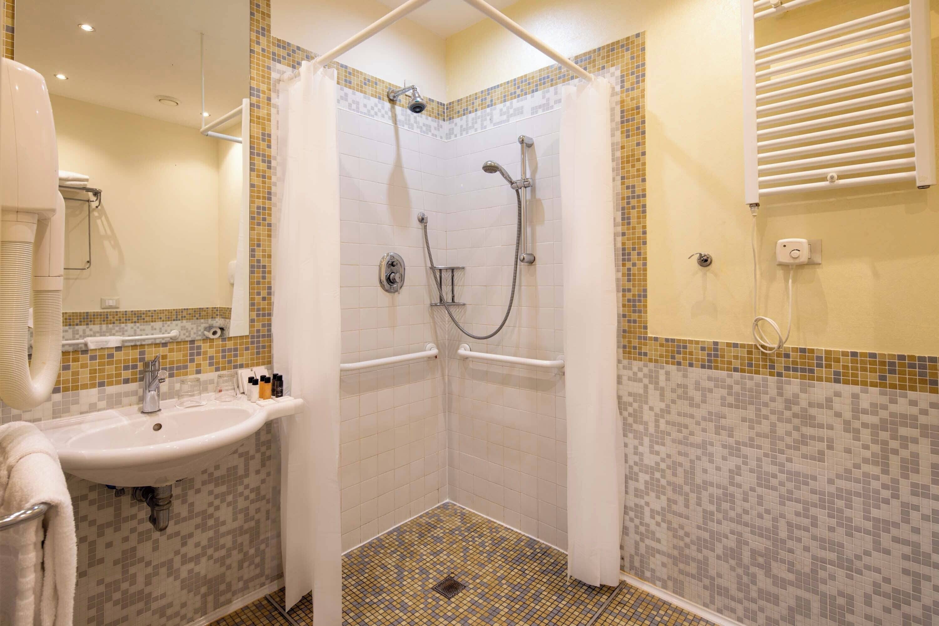 Une salle de bain avec douche, lavabo et carrelage au sol.