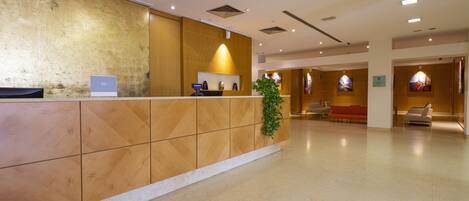 A reception area with a wooden reception desk, a potted plant, and a seating area with chairs and a sofa.