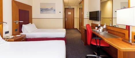 A hotel room with two beds, a desk with a chair, a television, and a large mirror.