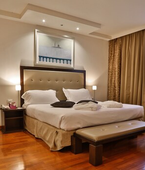 Un lit bien fait, avec une tête de lit, une table de chevet avec une lampe et un banc au pied du lit.