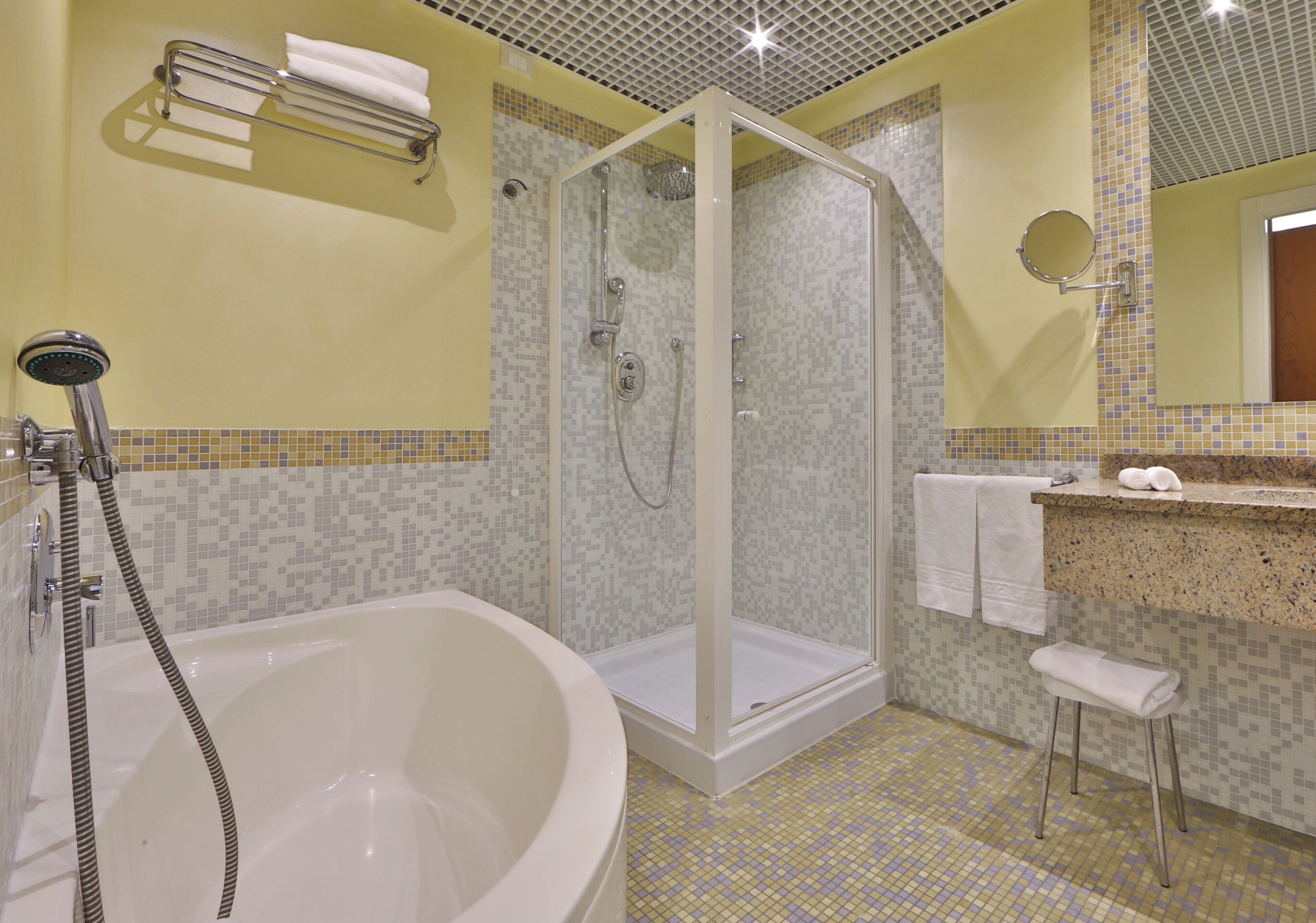 Un bagno con doccia vetrata, una vasca da bagno freestanding, un lavabo con specchio e un porta asciugamani.